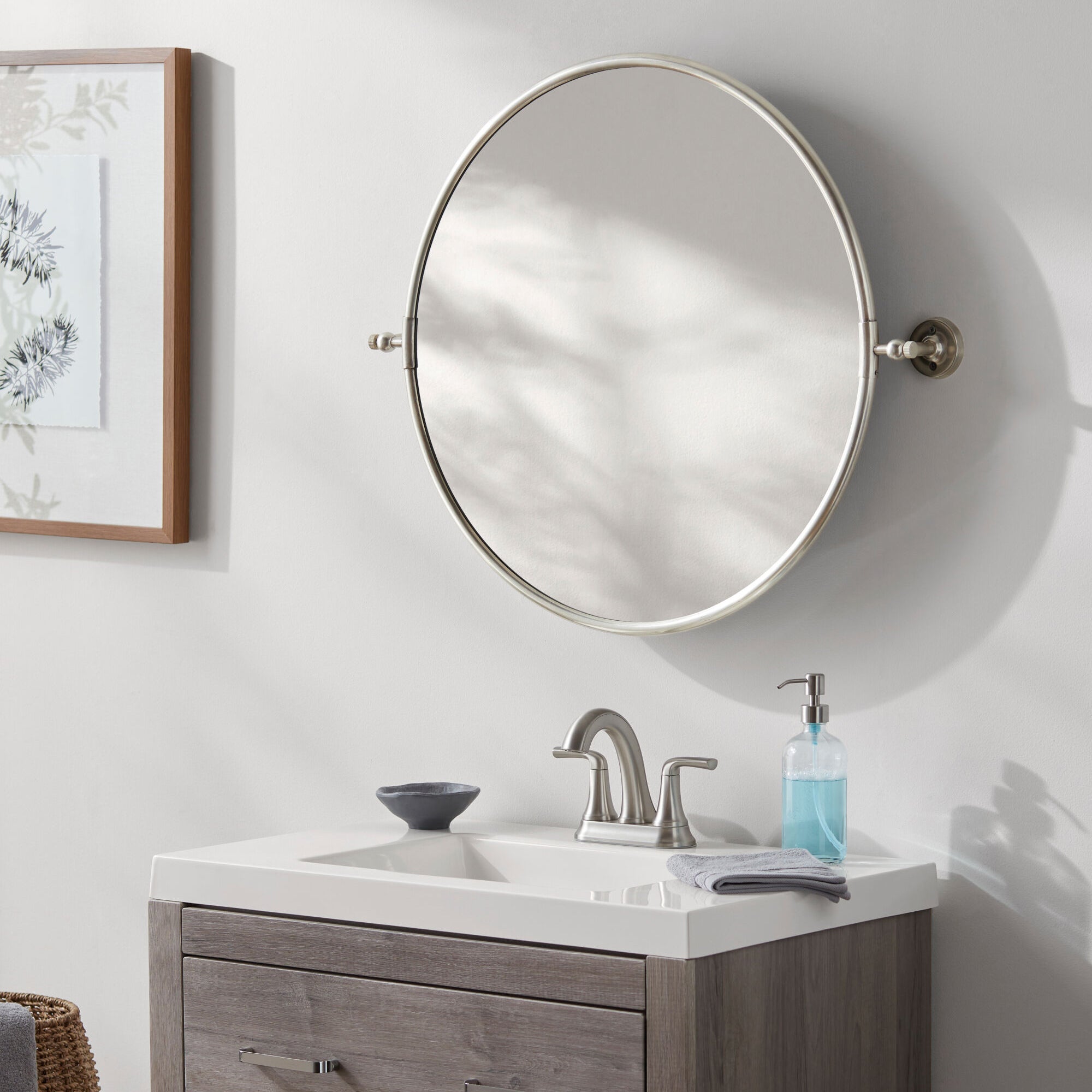 Burnish Round Accent Mirror in Antiqued Silver on a white wall in a bathroom at Addison West