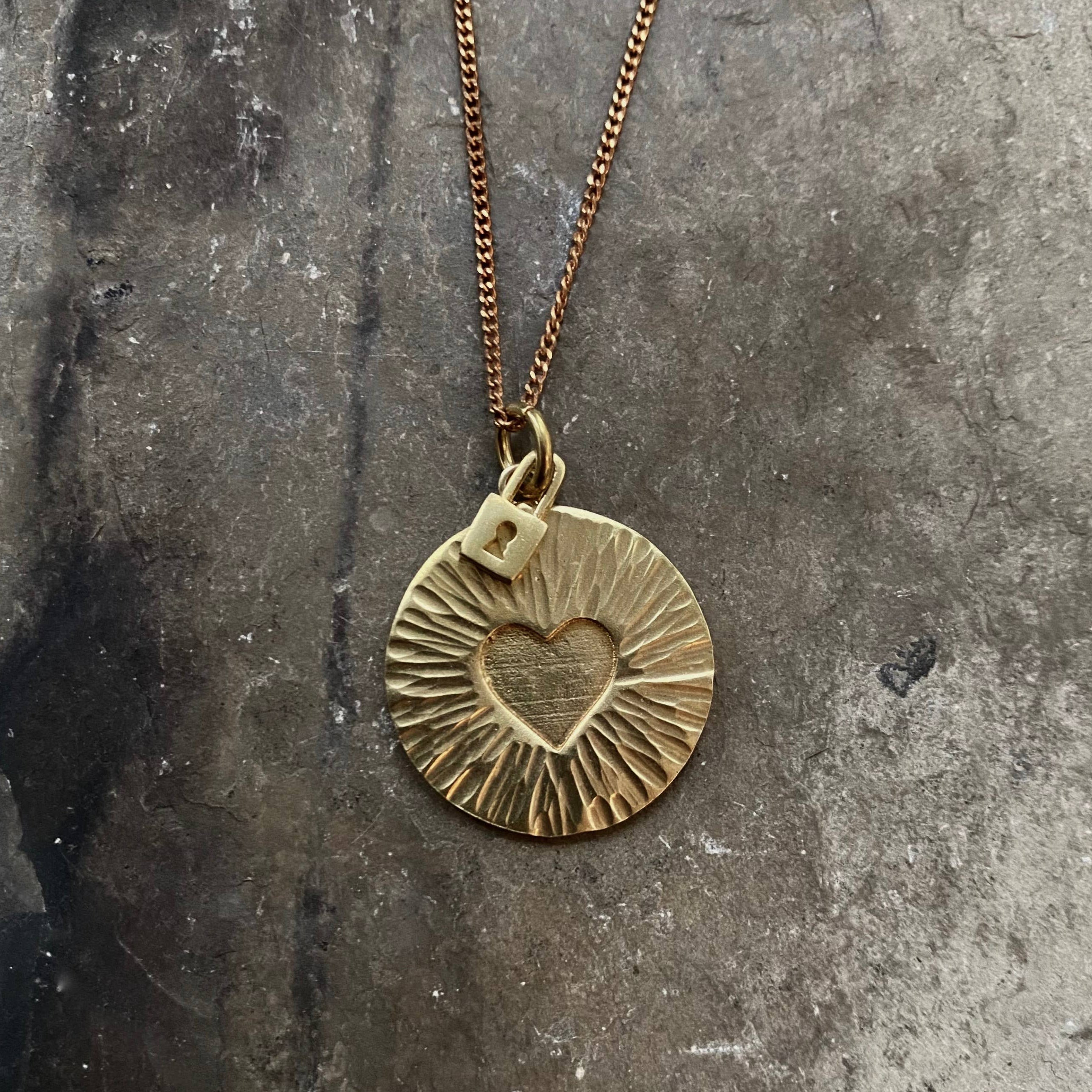 Tiny Anvil Brass Vault Necklace on a grey background at Addison West