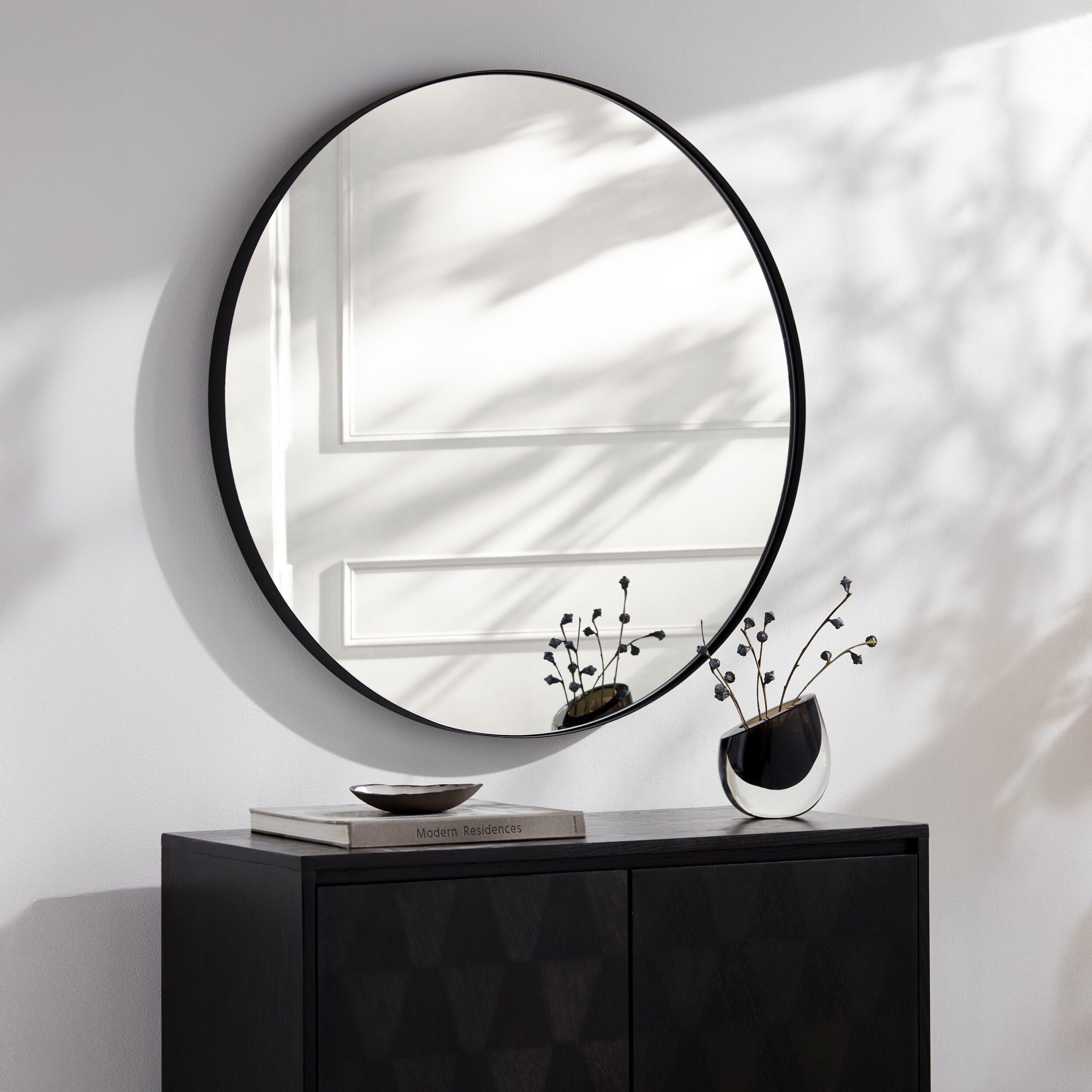 Carbondale Accent Mirror in Matte Black on a white wall above a table at Addison West