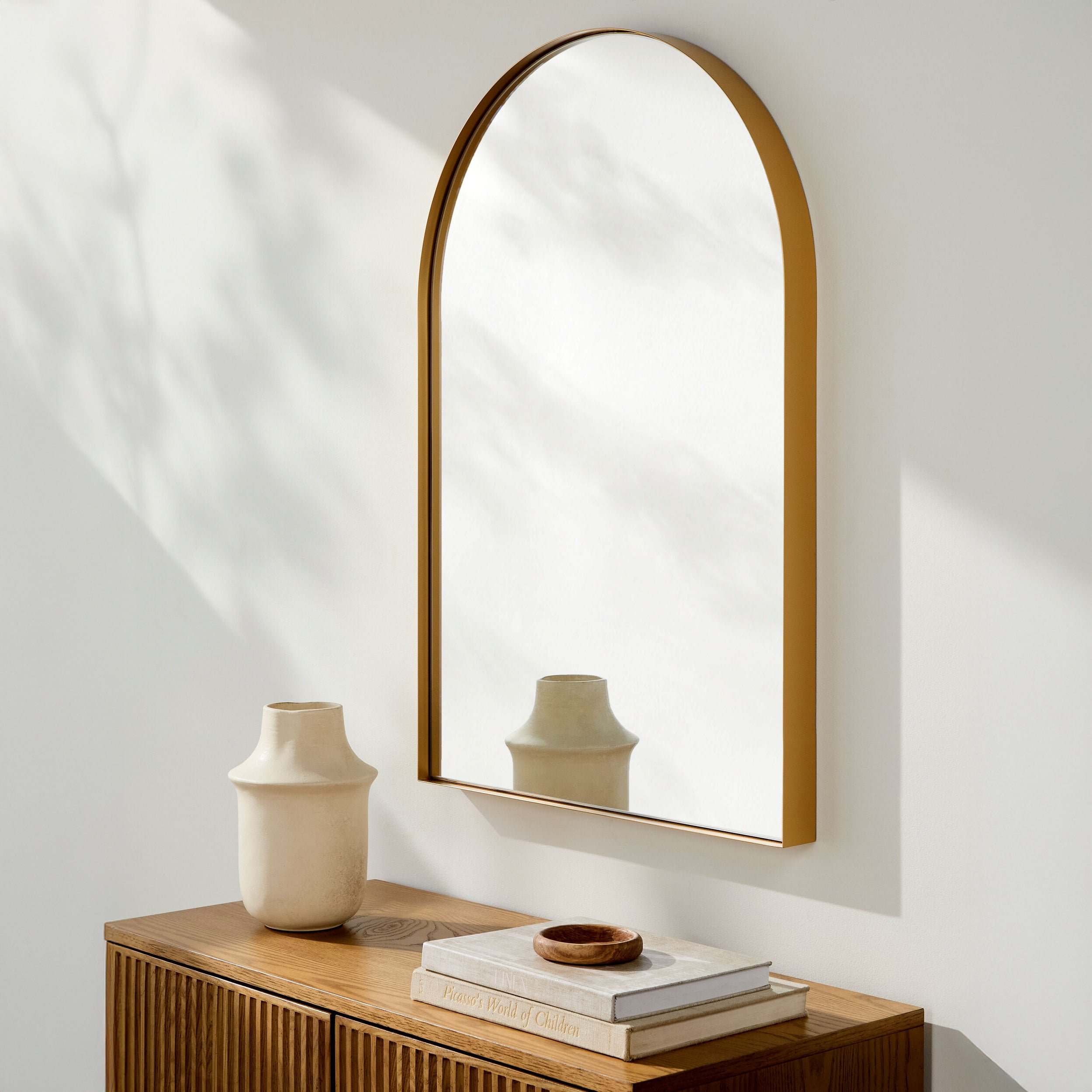 Carbondale Arch Accent Mirror on a white wall above a table at Addison West