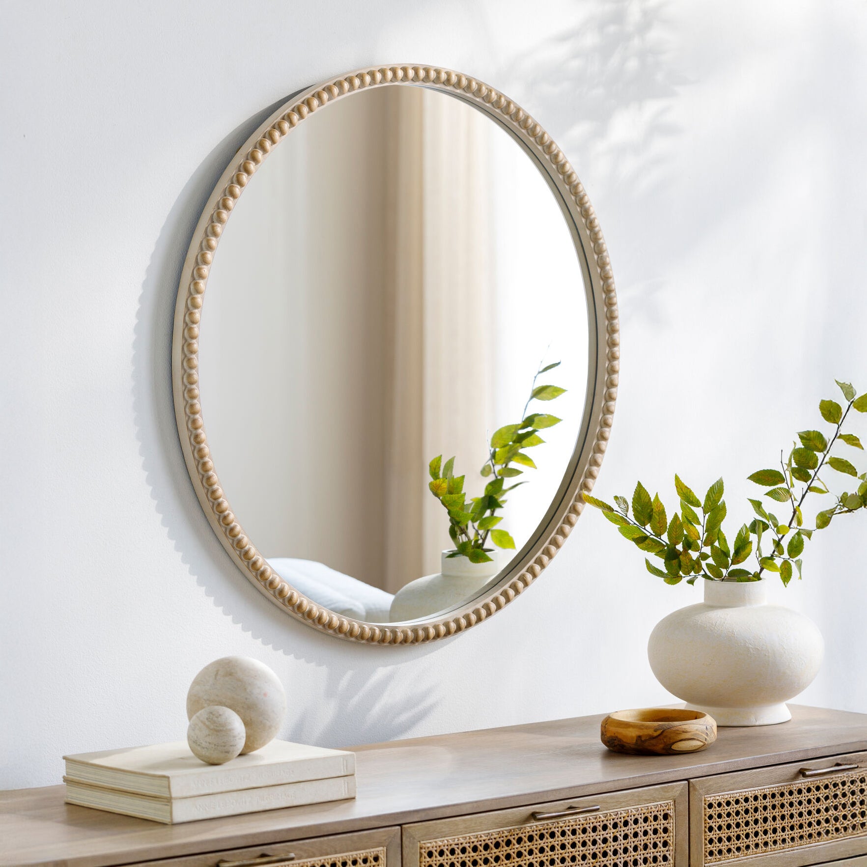 Dwarka Accent Mirror on a white wall above a table at Addison West