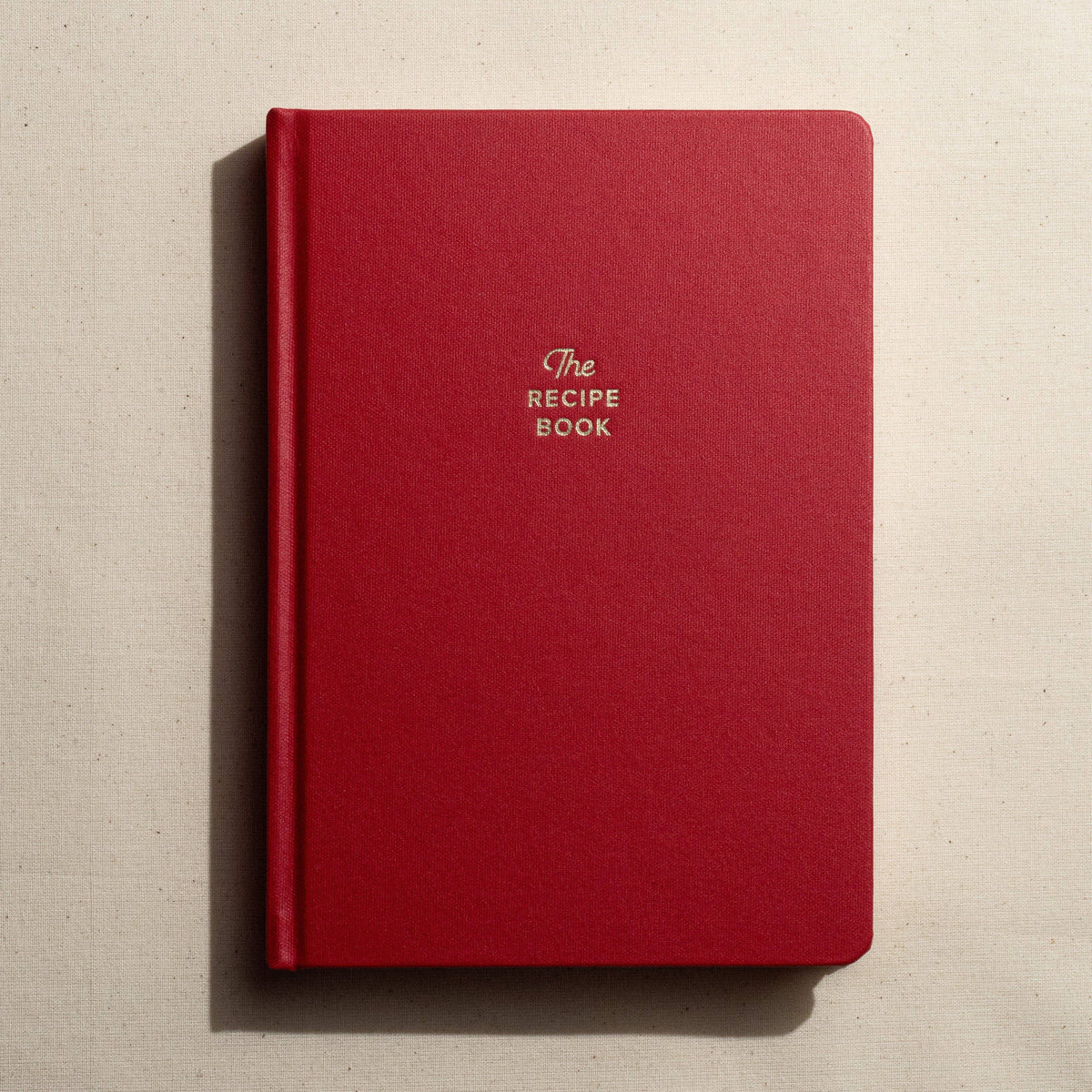 Red notebook titled 'The Recipe Book' on a beige background