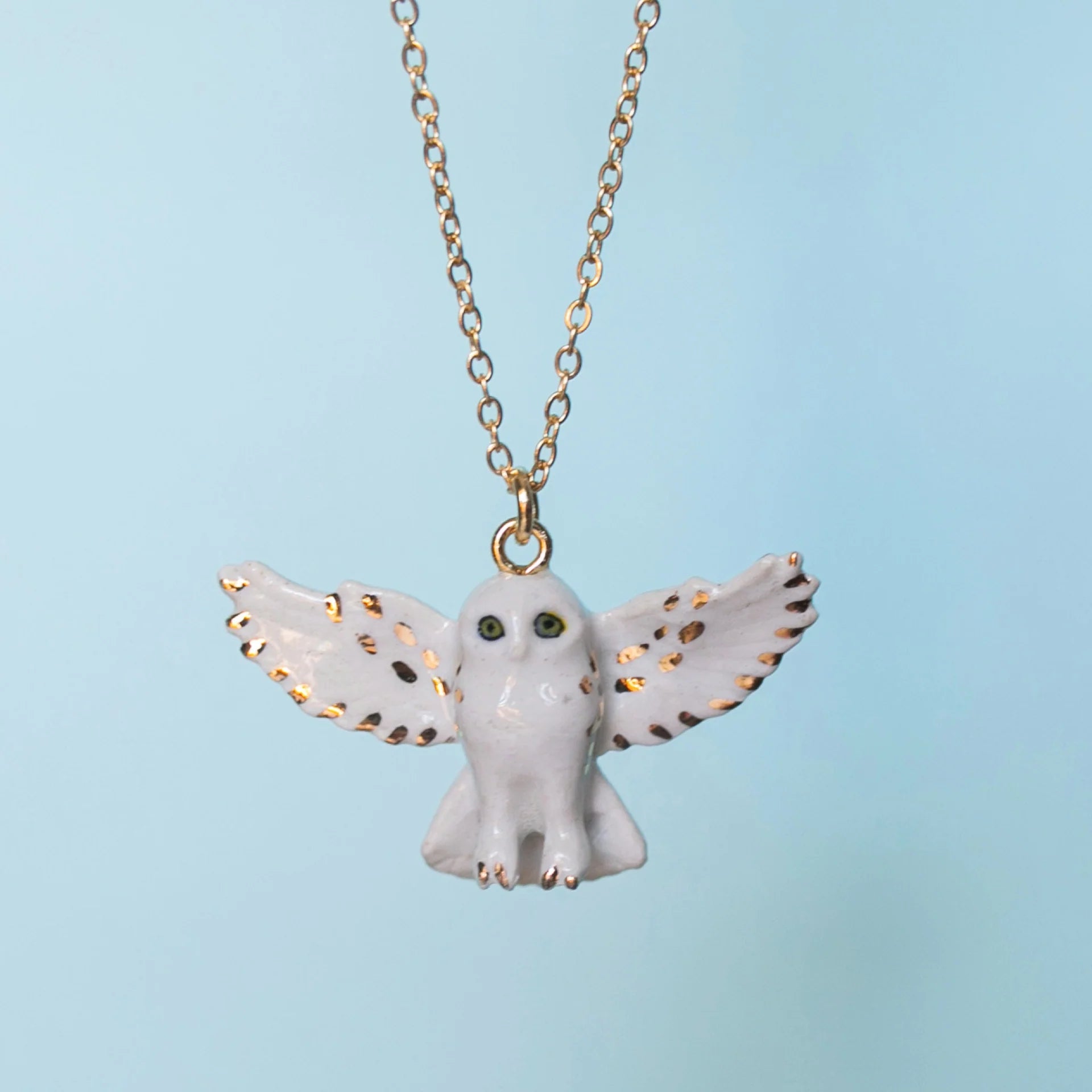 Golden Snowy Owl Necklace on a blue background at Addison West
