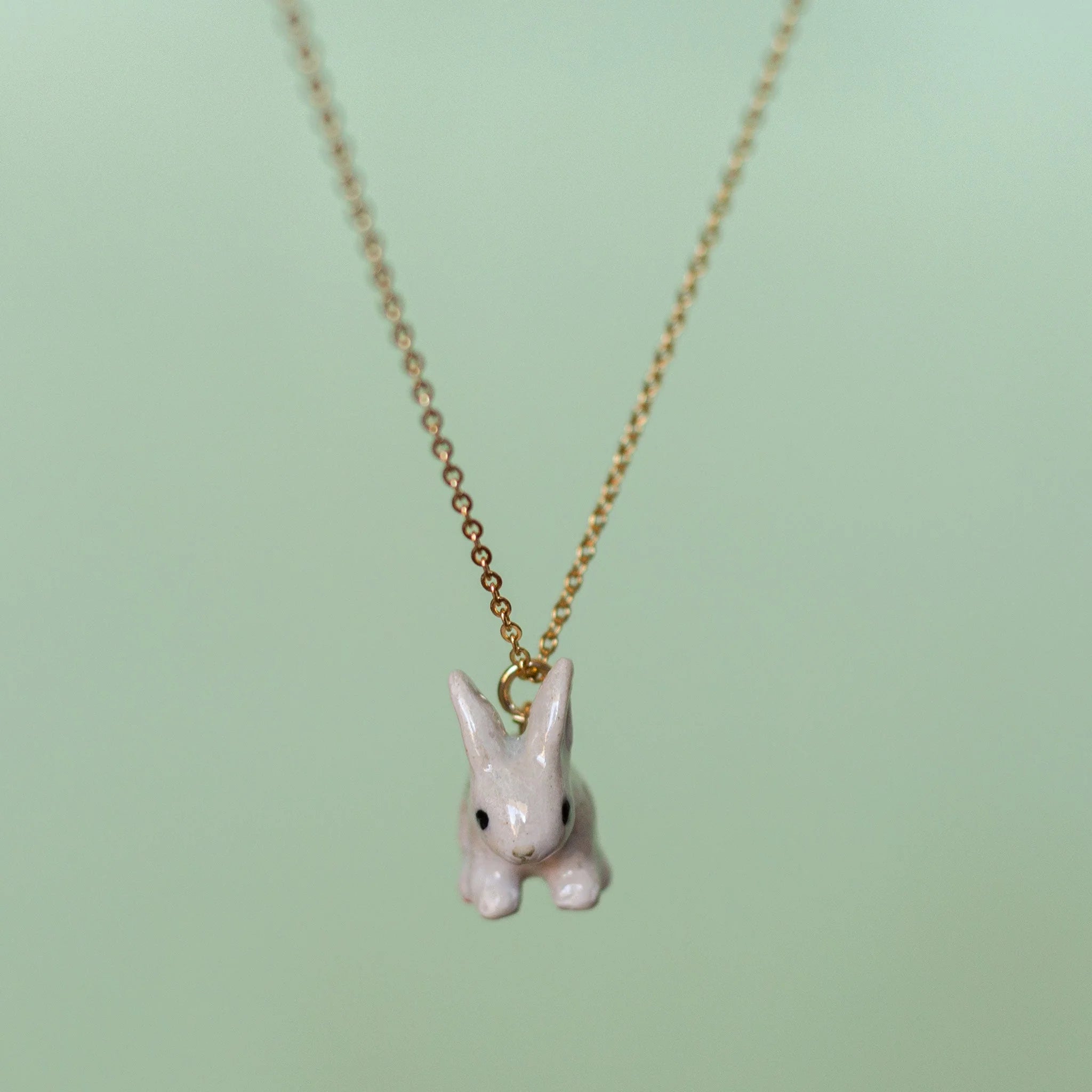 Camp Hollow Porcelain Goldentail Rabbit Necklace on green background.