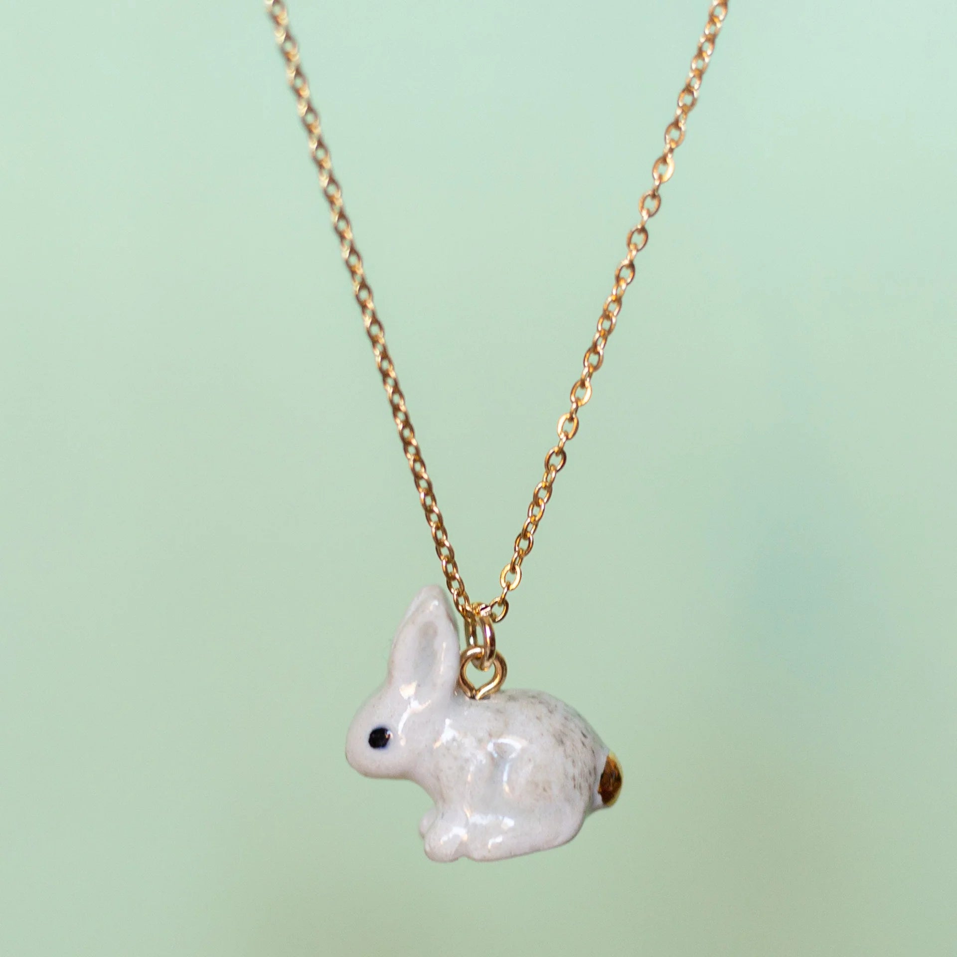Camp Hollow Porcelain Goldentail Rabbit Necklace on green background.