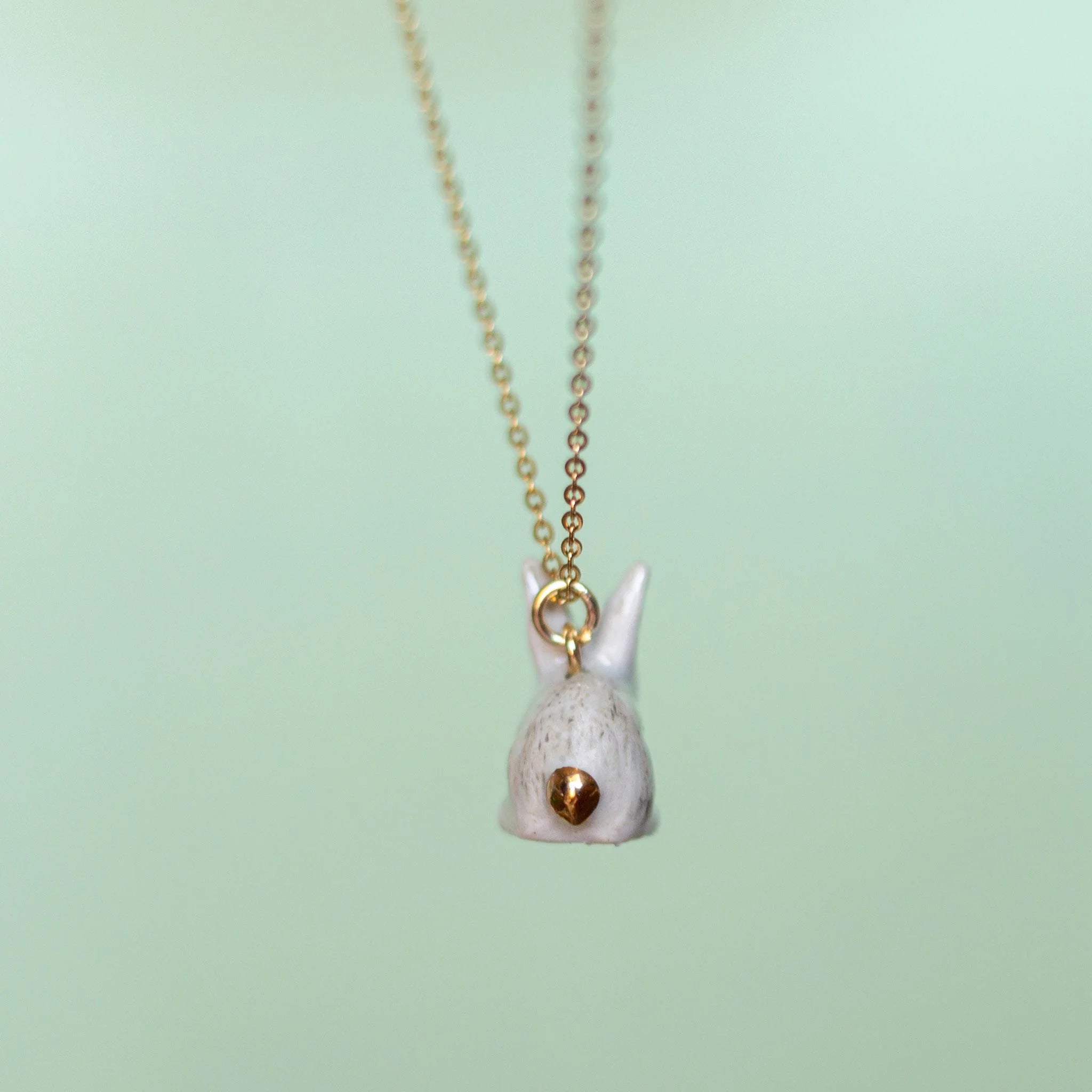 Camp Hollow Porcelain Goldentail Rabbit Necklace on green background.