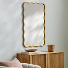 Ismenia Accent Mirror on a white wall above a table at Addison West