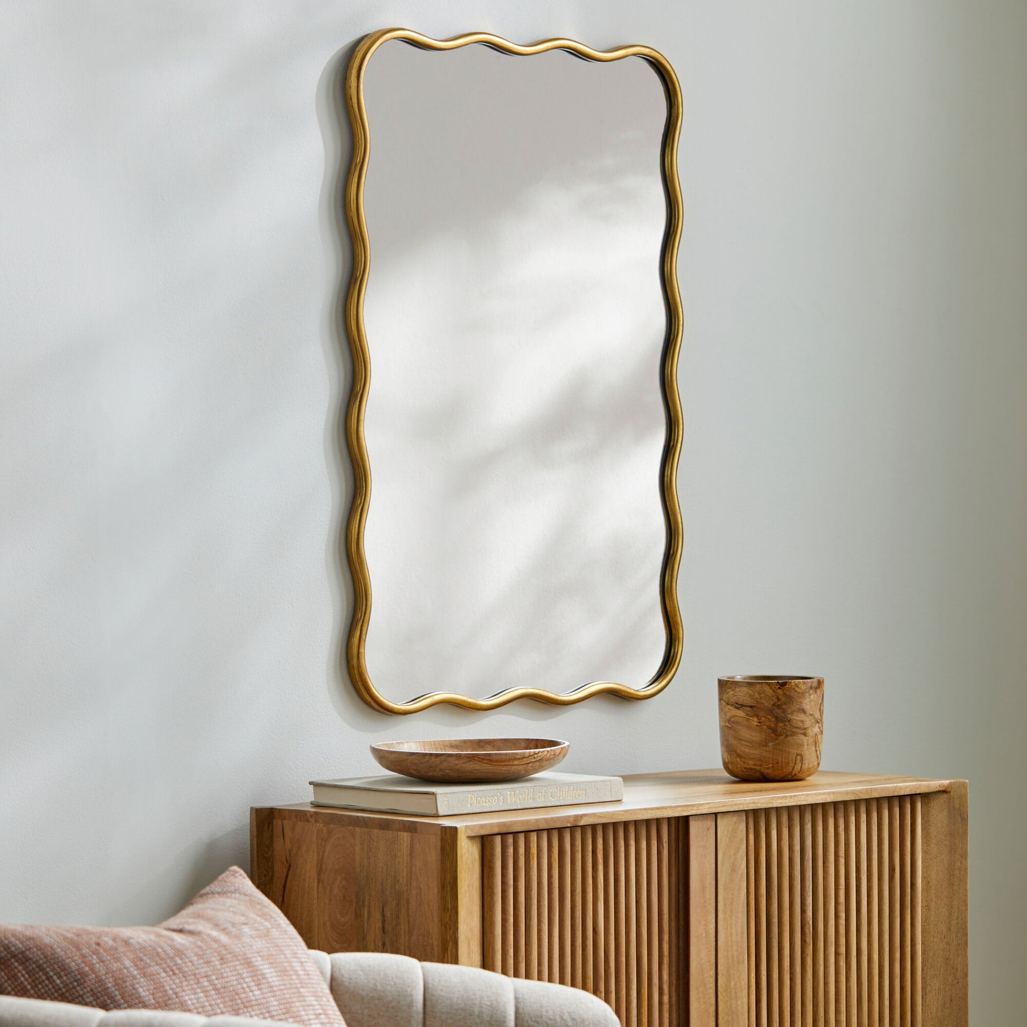 Ismenia Accent Mirror on a white wall above a table at Addison West