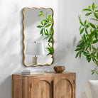 Ismenia Accent Mirror on a white wall above a table at Addison West