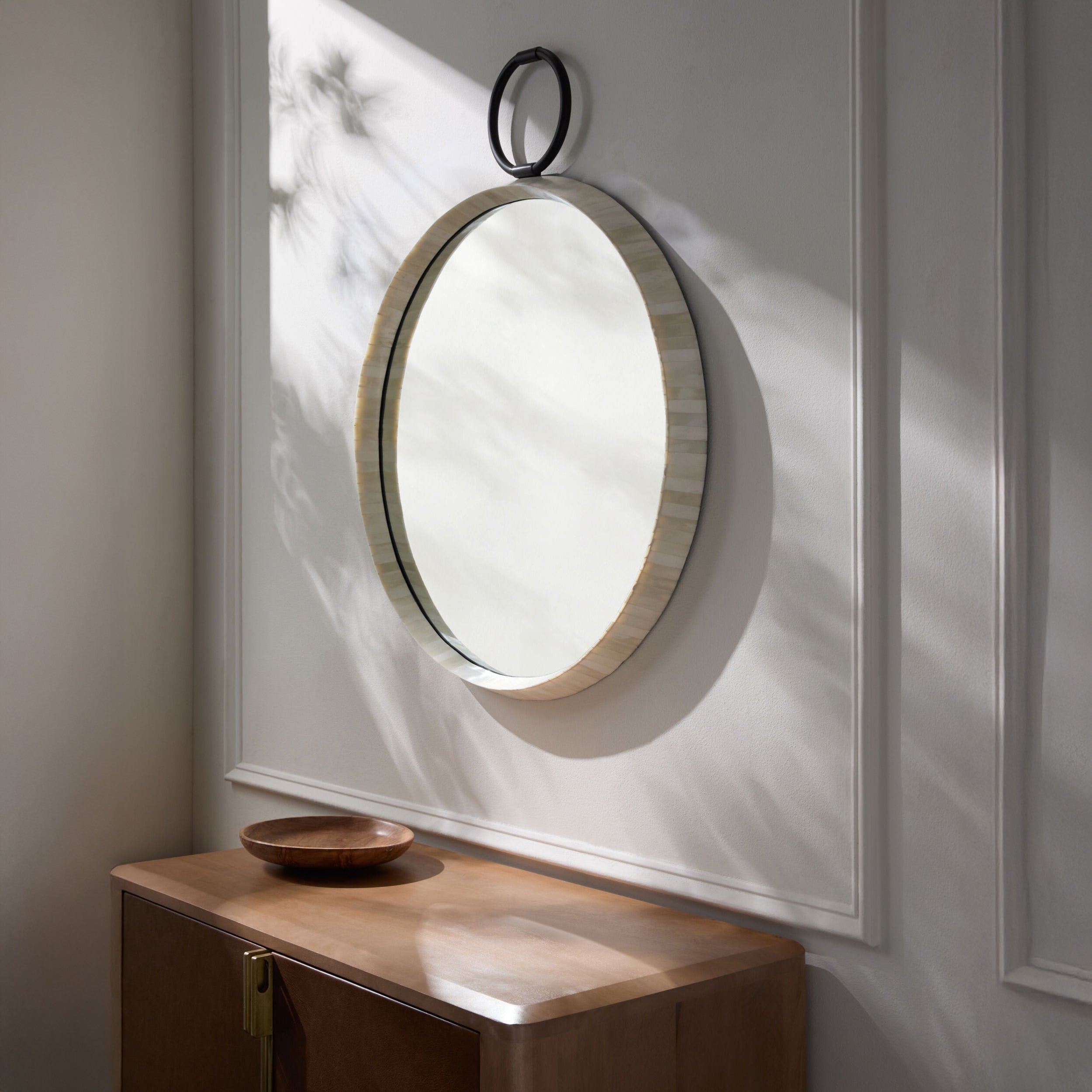 Opale Accent Mirror on a white wall above a table at Addison West