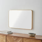 Aranya Accent Mirror on a white wall above a table at Addison West