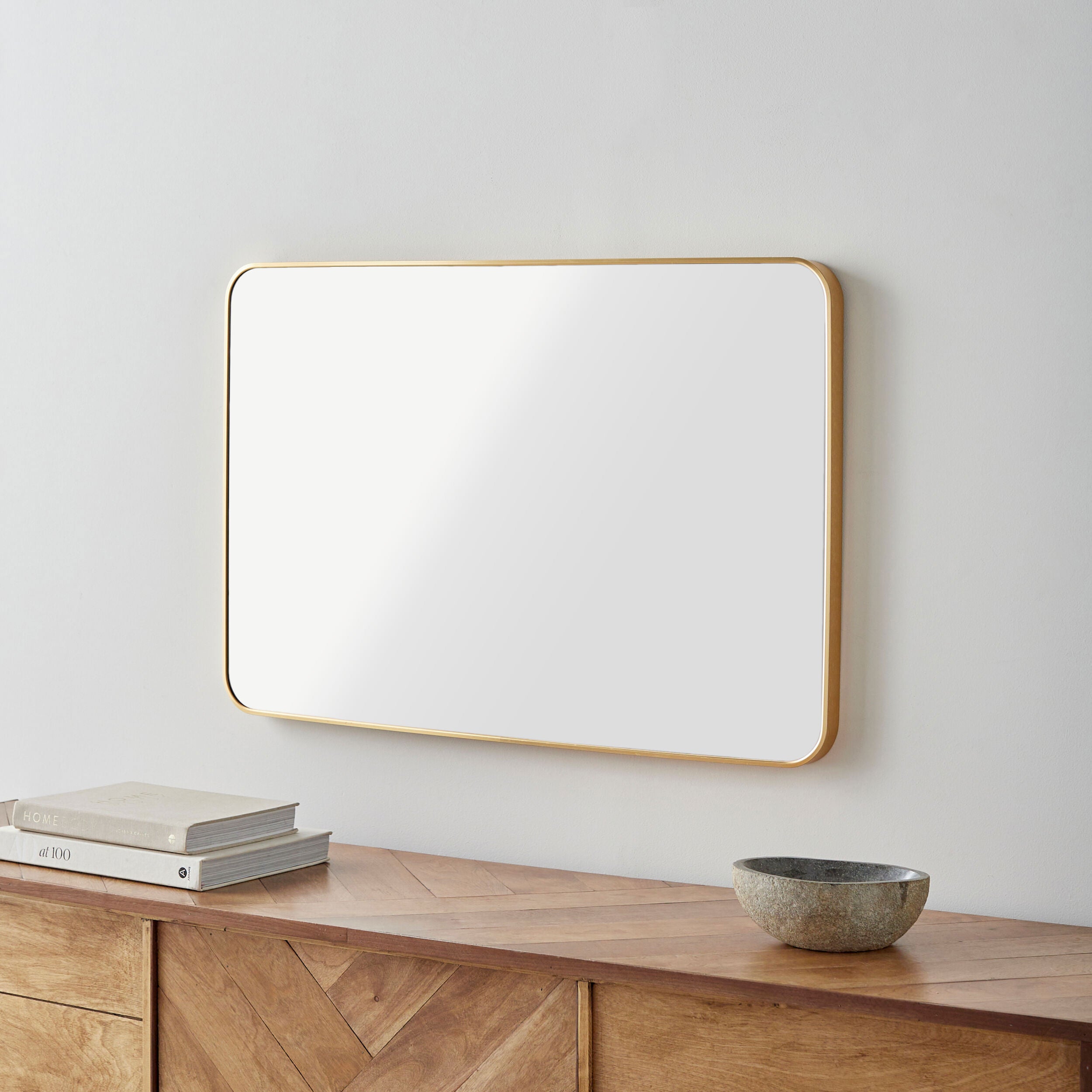 Aranya Accent Mirror on a white wall above a table at Addison West