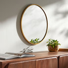 Carmen Accent Mirror on a white wall above a table at Addison West