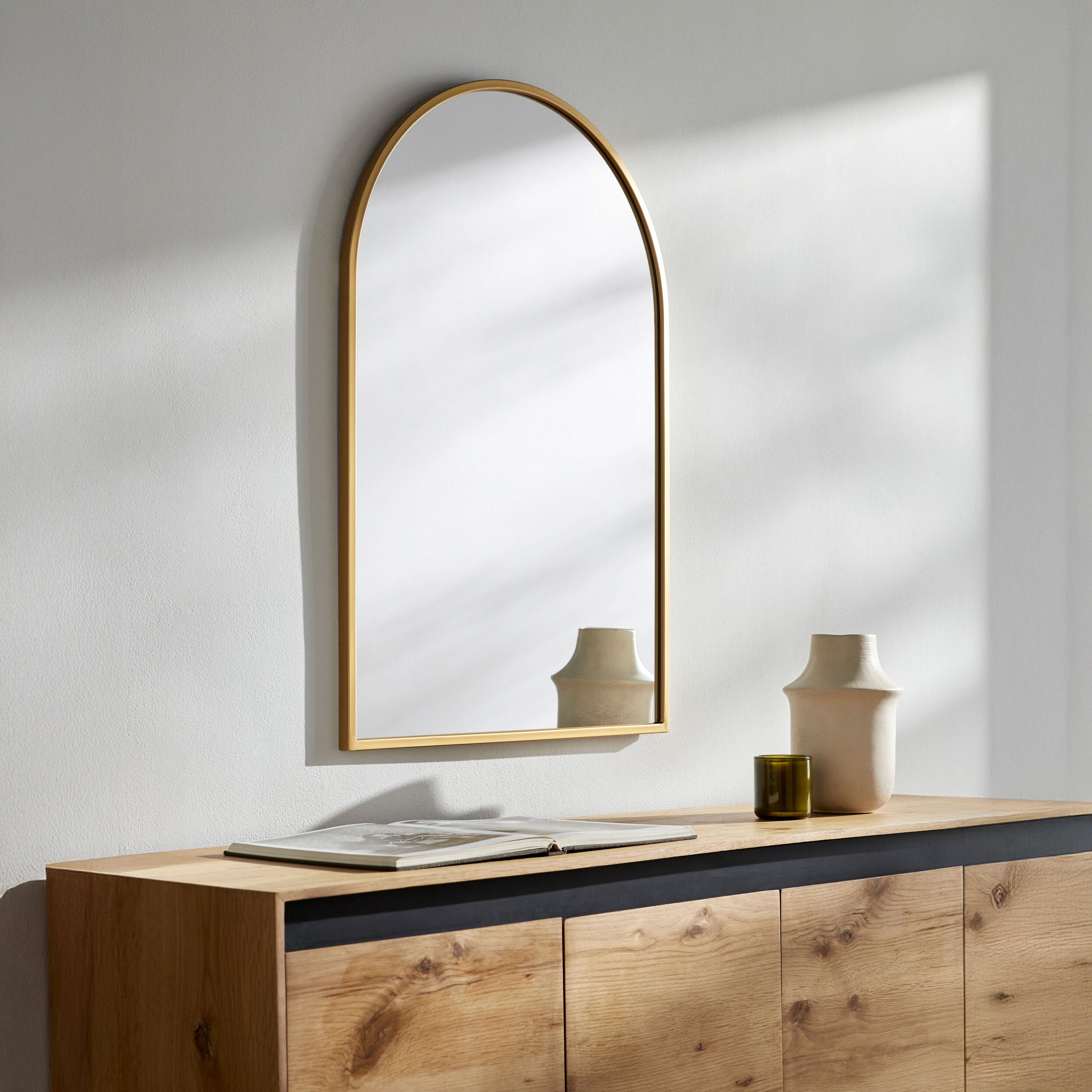 Carmen Arch Accent Mirror on a white wall above a table at Addison West