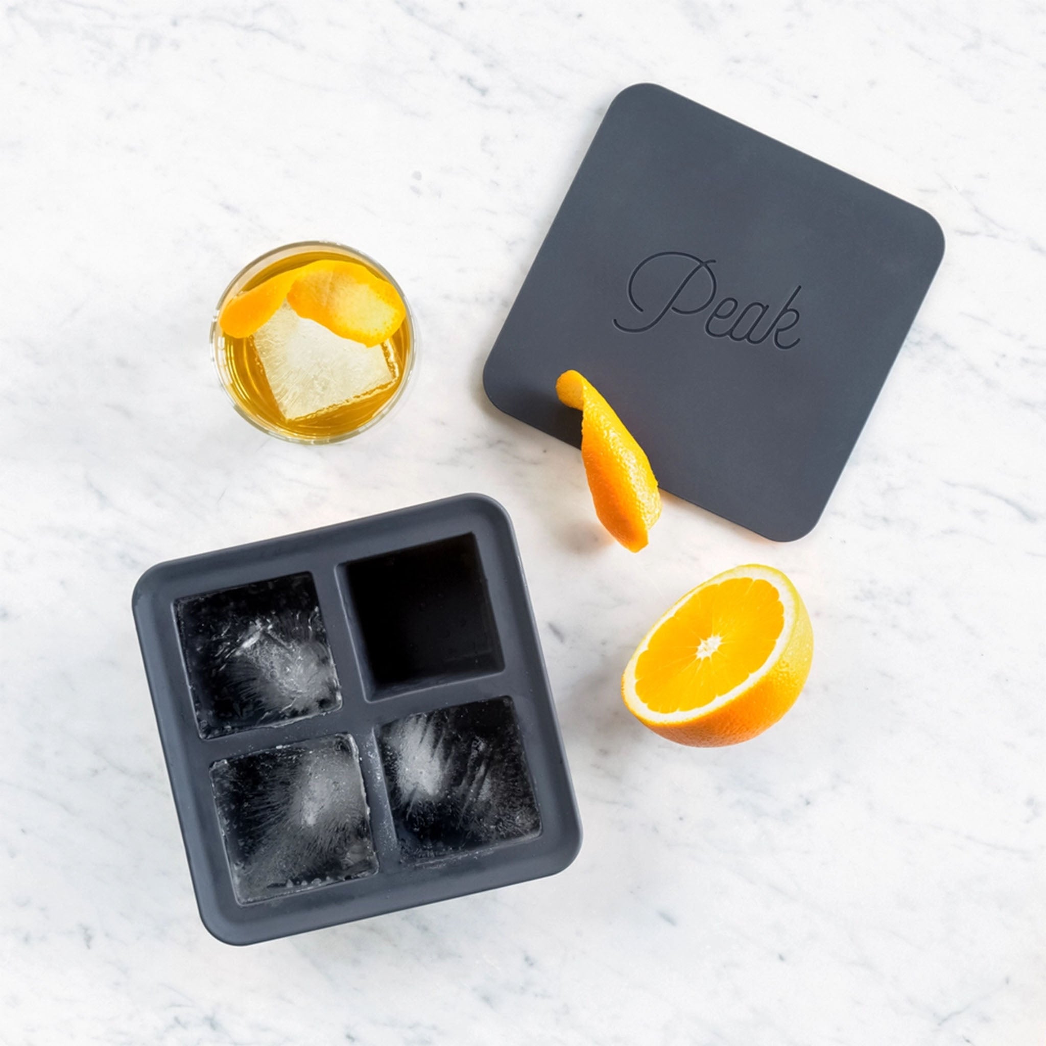 Silicon square ice cube tray by peak on a marble surface with orange and cocktail