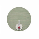 Chilewich Bamboo Signature round placemat in spring green color on a white background with a small plate and white spoon