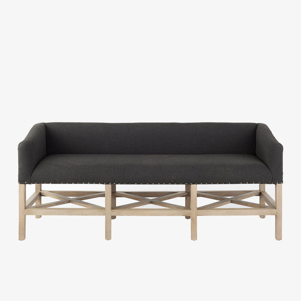 Grey upholstered accent bench with trellis wood base and small bolster back and nail head finish