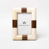 White bone picture frame with strip of wood accents on each side on a white background. 