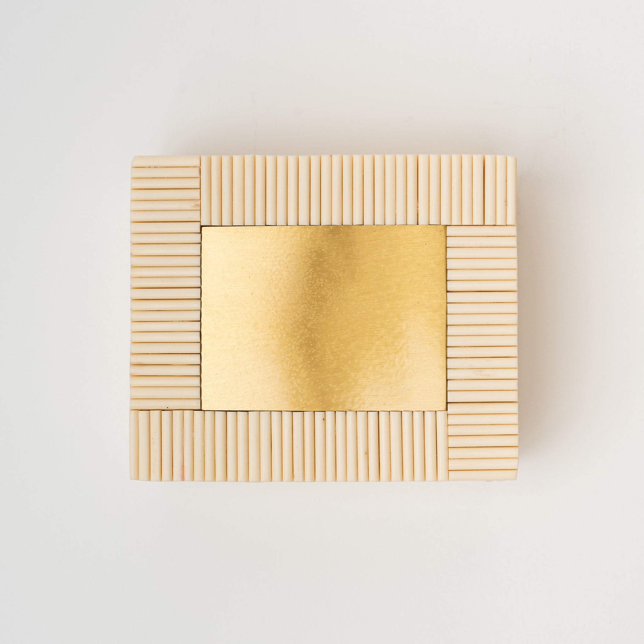 White rectangular box made of bone Redding with brass inset on a white background