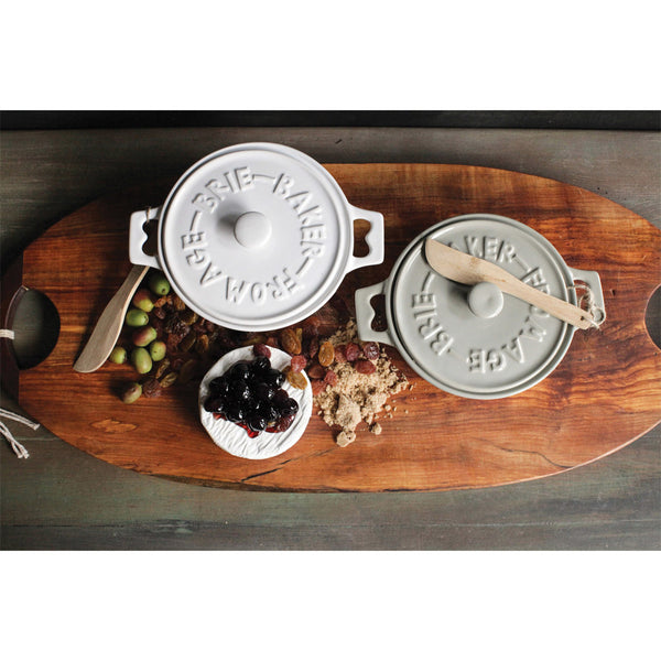 Wood board with two brie bakers in grey and white on a countertop
