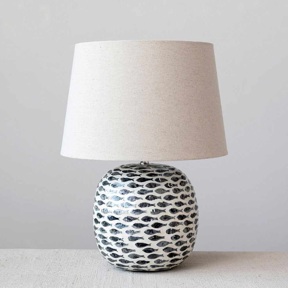 Round table lamp with inlay fish pattern and linen shade on a white table 