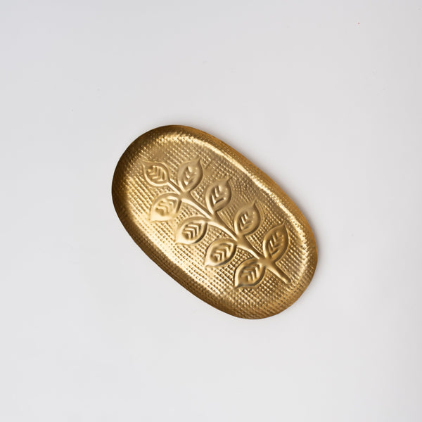 Embossed brass colored iron tray with leaf pattern on a white background