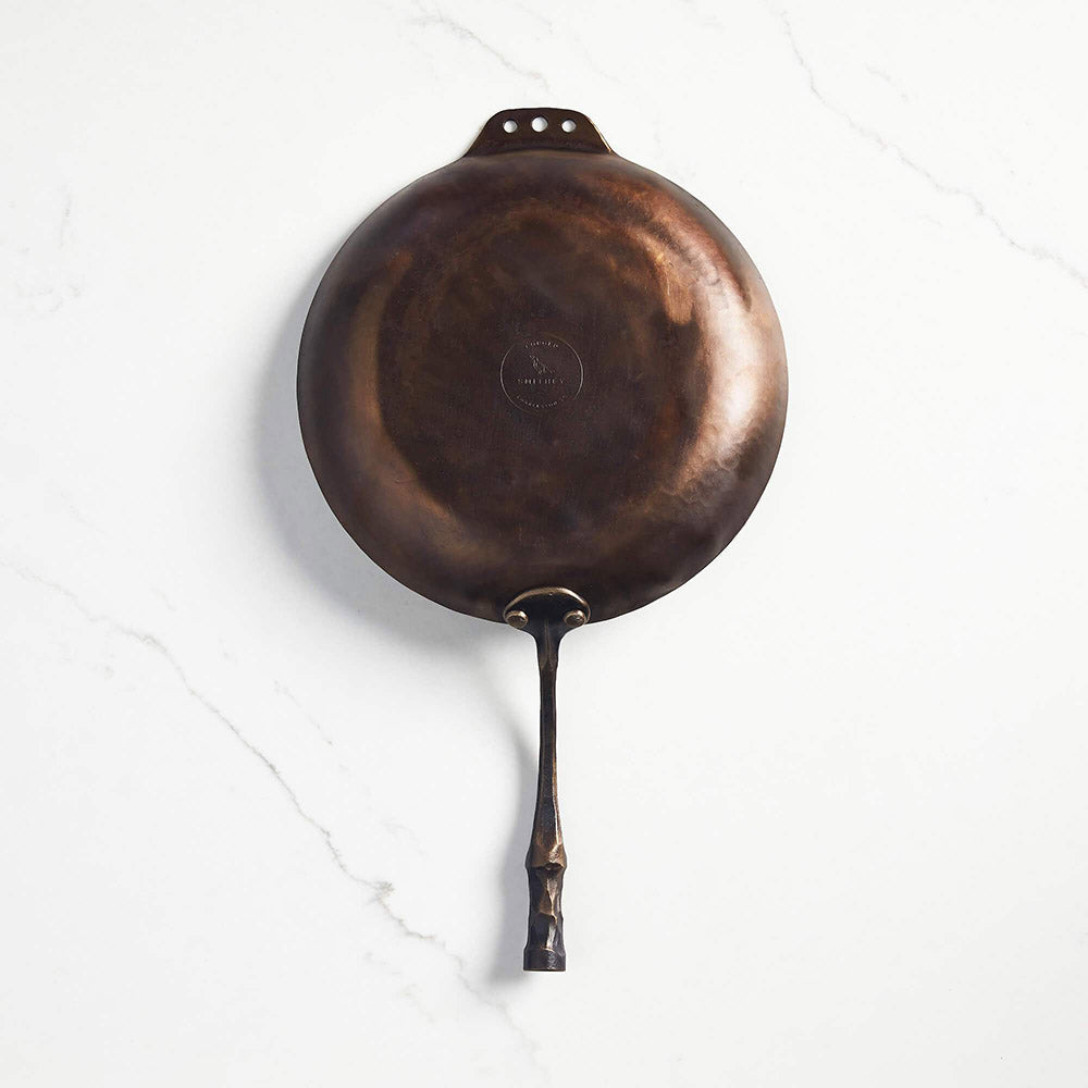 Underside of Smithey farmhouse carbon steep skillet on a white background