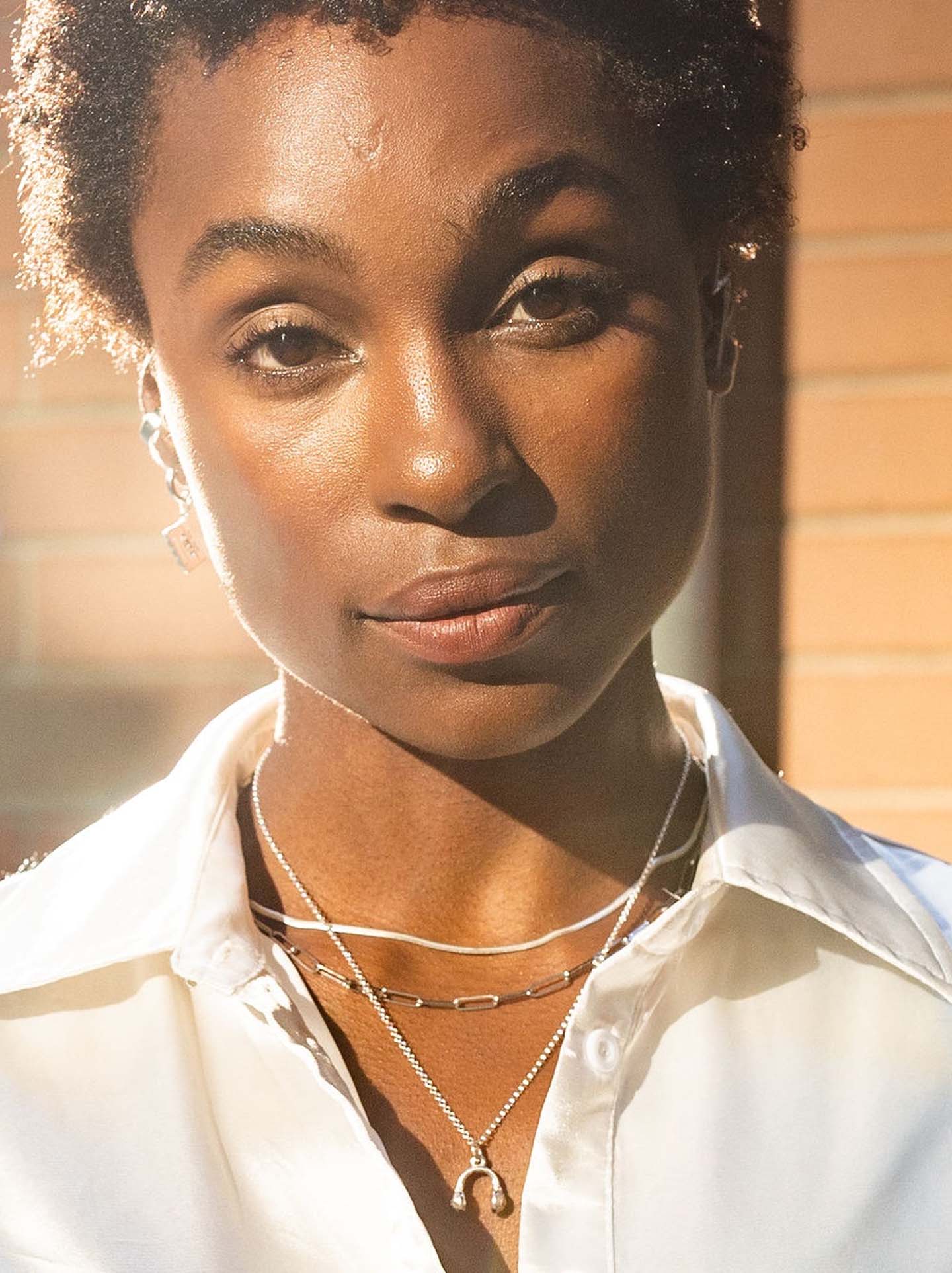 Scream pretty brand gold headphones necklace on a model with white shirt