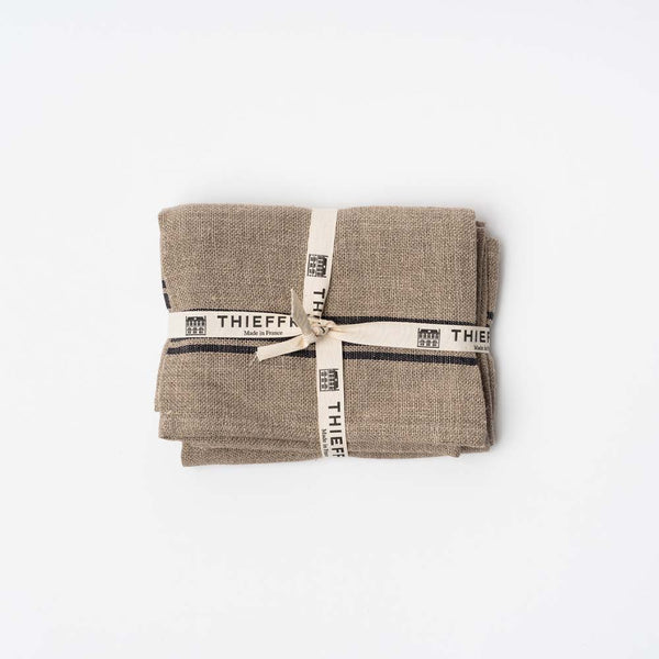 Set of two natural with black stripe Thieffry Belgian Linen kitchen tea towels on a white background tied with a bow