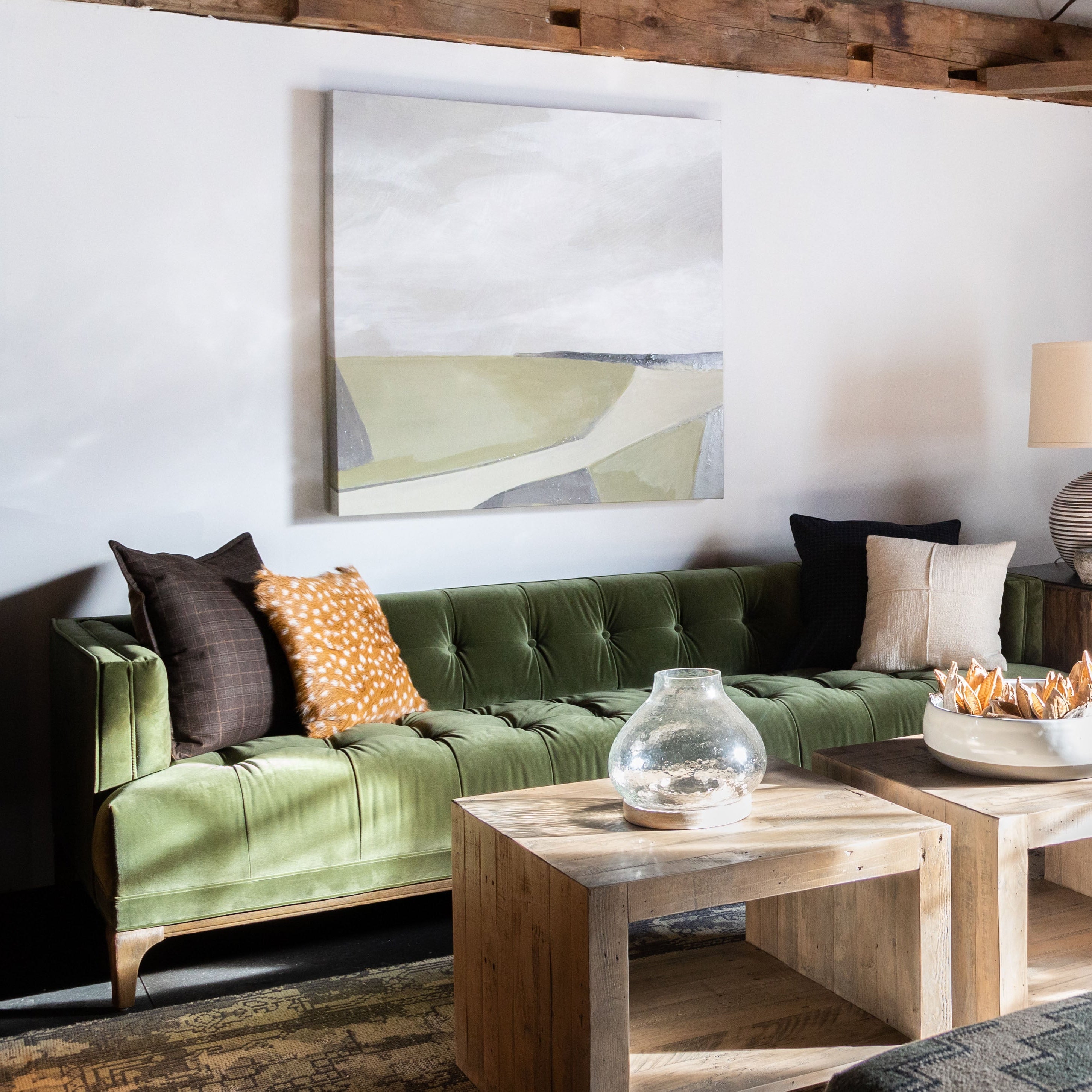 Living room area with Four hands brand green velvet Dylan sofa with paintingw with wood coffee table in front and grey armchair