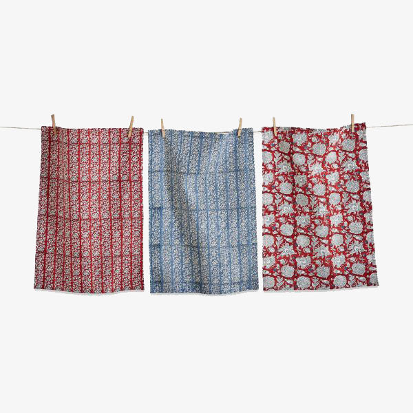 Set of three block print red and blue Kitchen Towels in check and stripe and botanical print on a clothes line in front of a white background