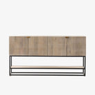 Four hands furniture brand Kelby media console with iron base and four white washed carved doors with square brass knobs on a white background