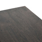 Close up of wood surface on Four hands furniture brand Kelby media console with iron base and four carved doors with square brass pulls on a white background