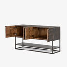 Four hands furniture brand Kelby media console with iron base and four carved doors with square brass pulls on a white background