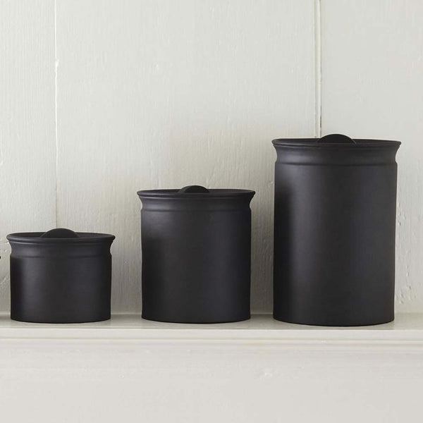 Three black Sir Madam brand crocks for kitchen on white counter with white background