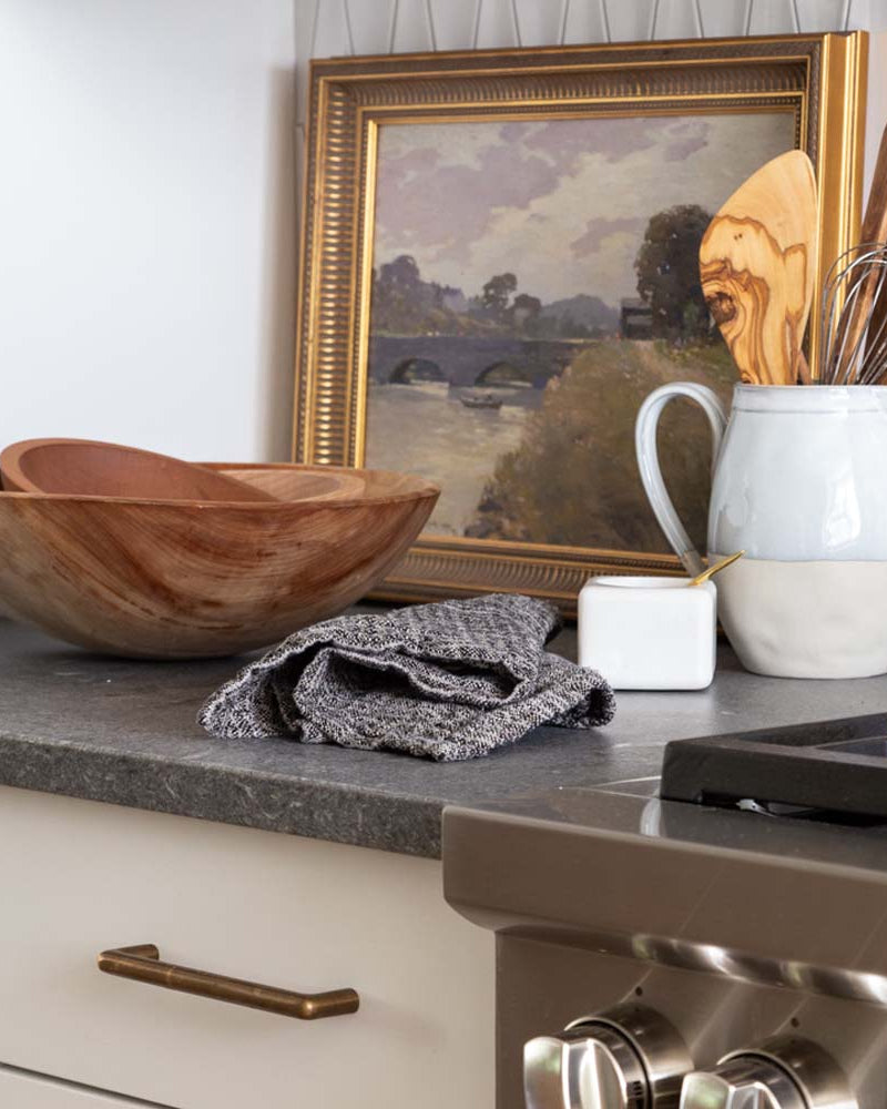 Wood salad bowls on a stone counter with painting and pitcher