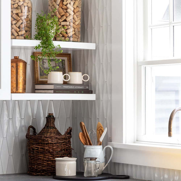 Sunny white kitchen with grey counter and shelves with crocks and books and plant