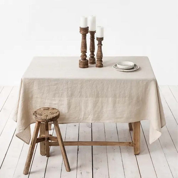 Table with natural linen tablecloth draped over it and a stool next to it