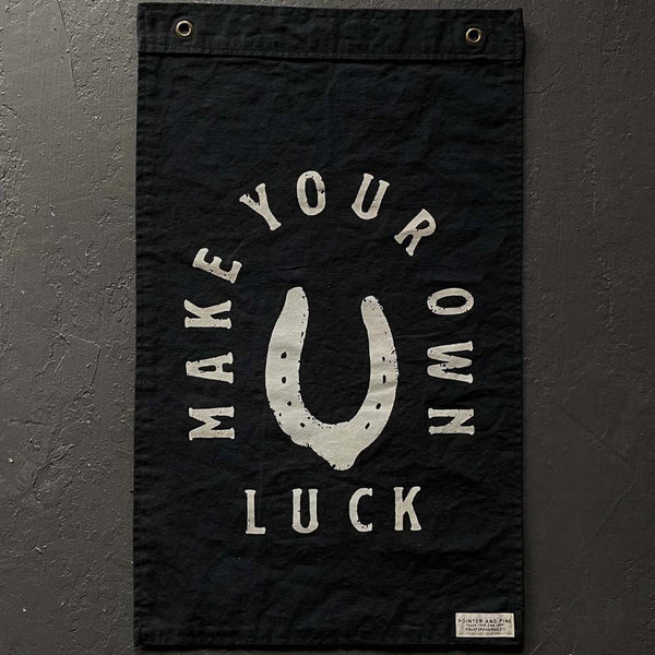 Pointer and Pine brand black flag with white words that say make your own luck