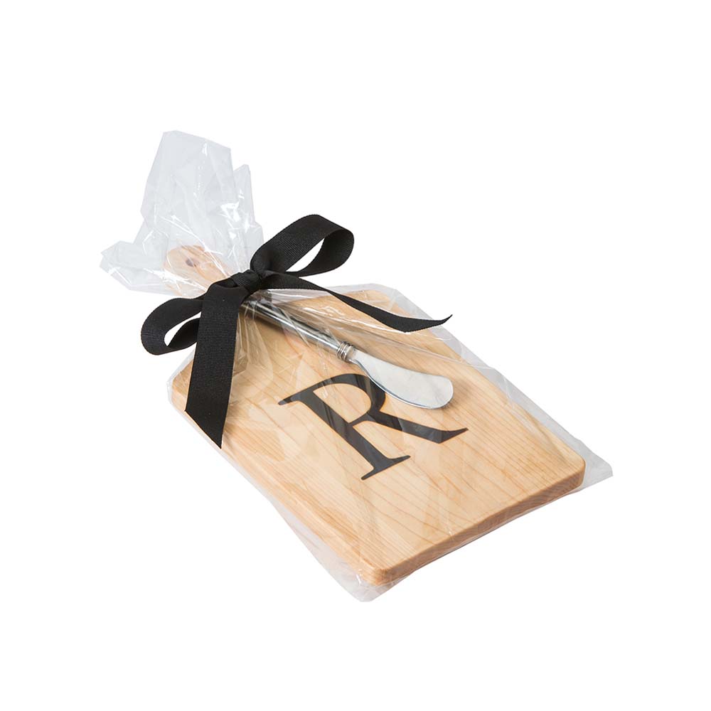 Monogramed maple cheese board with letter 'M' engraved and a stainless cheese knife wrapped in a cellophane sleeve on a white background