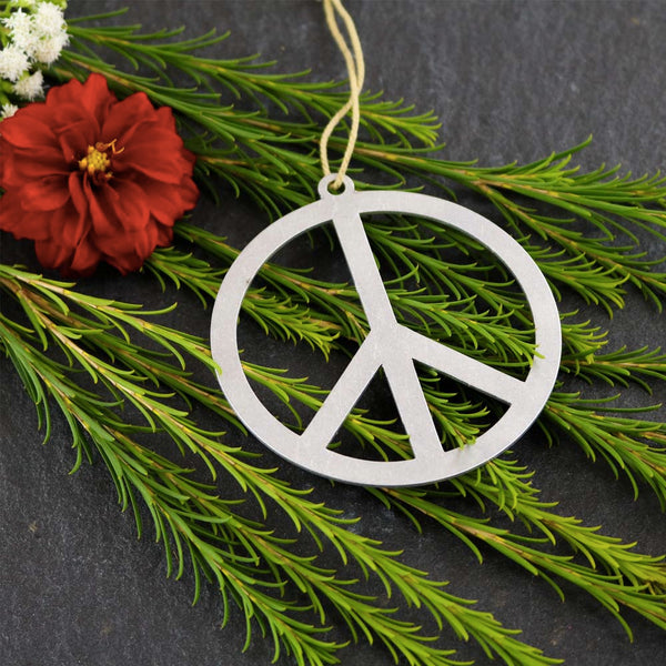Brushed aluminum metal peace sign ornament on a green background