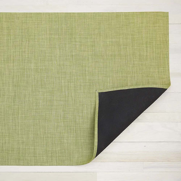 Chilewich mini basketweave woven floor mat in green dill color on light wood floor