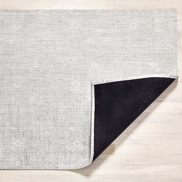 Chilewich mosaic woven floor mat in grey on a light wood floor