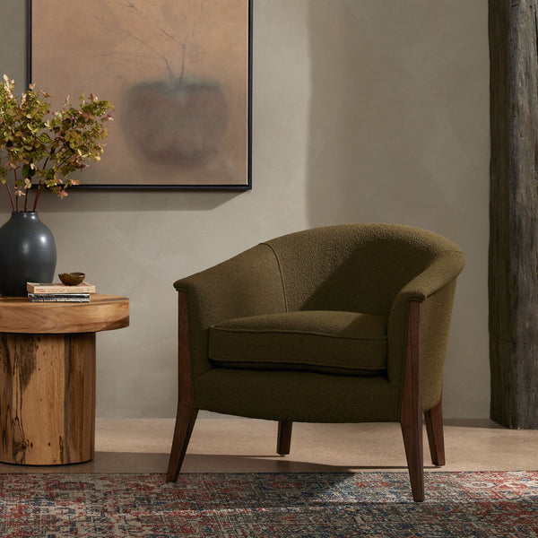 Grey upholstered 'nomad' arm chair by Four Hands Furniture with dark wood frame and rounded back in a living space with grey walls and patterned rug