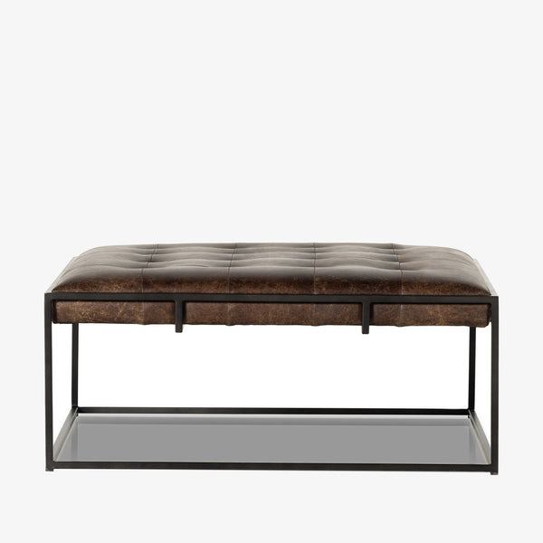 Four hands brand Oxford square coffee table with black iron frame frame and distressed brown leather top on a white background