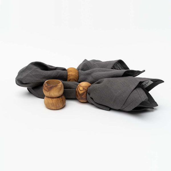 Set of four olive wood napkin rings two shown with grey linen napkins