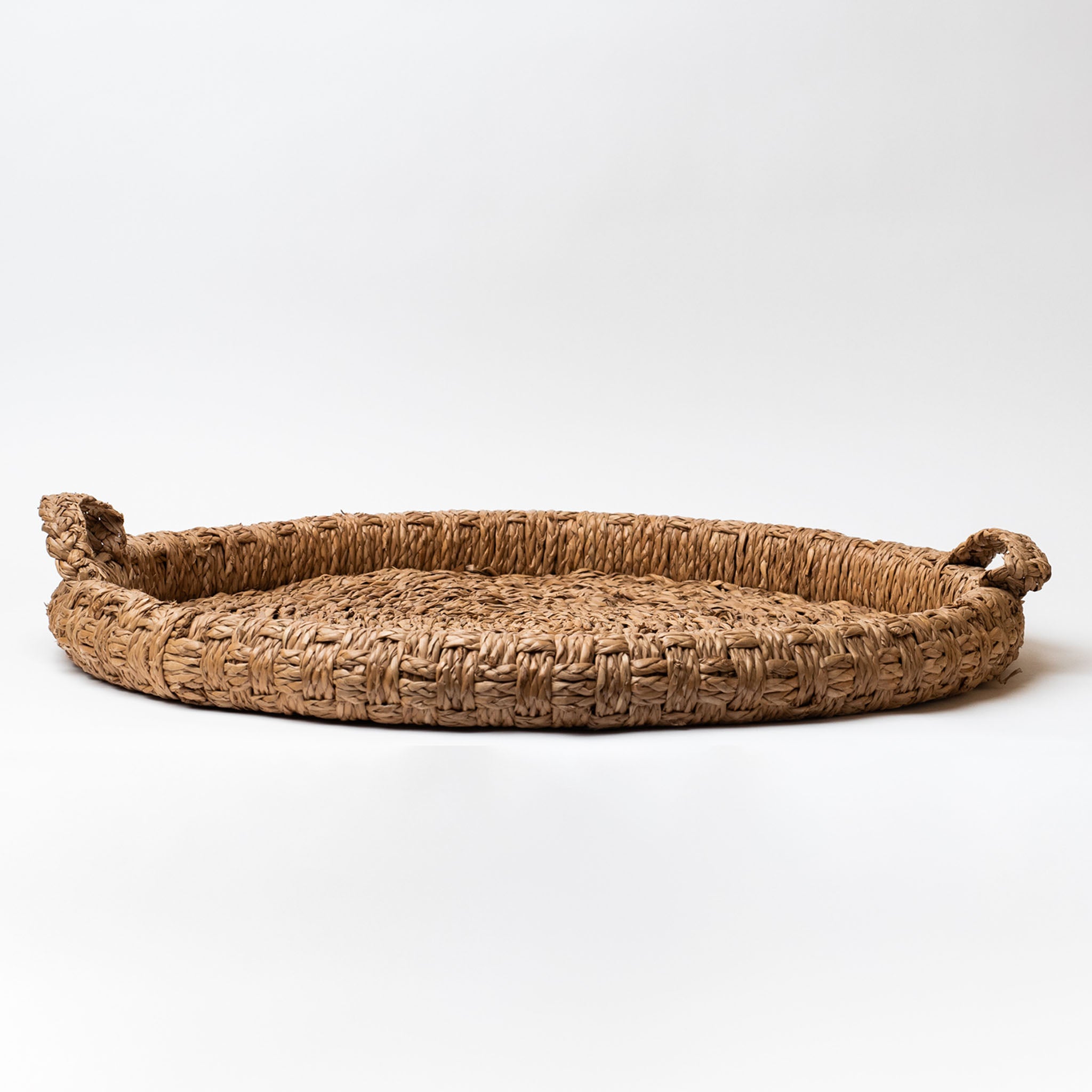 Round seagrass tray with handles on a white background