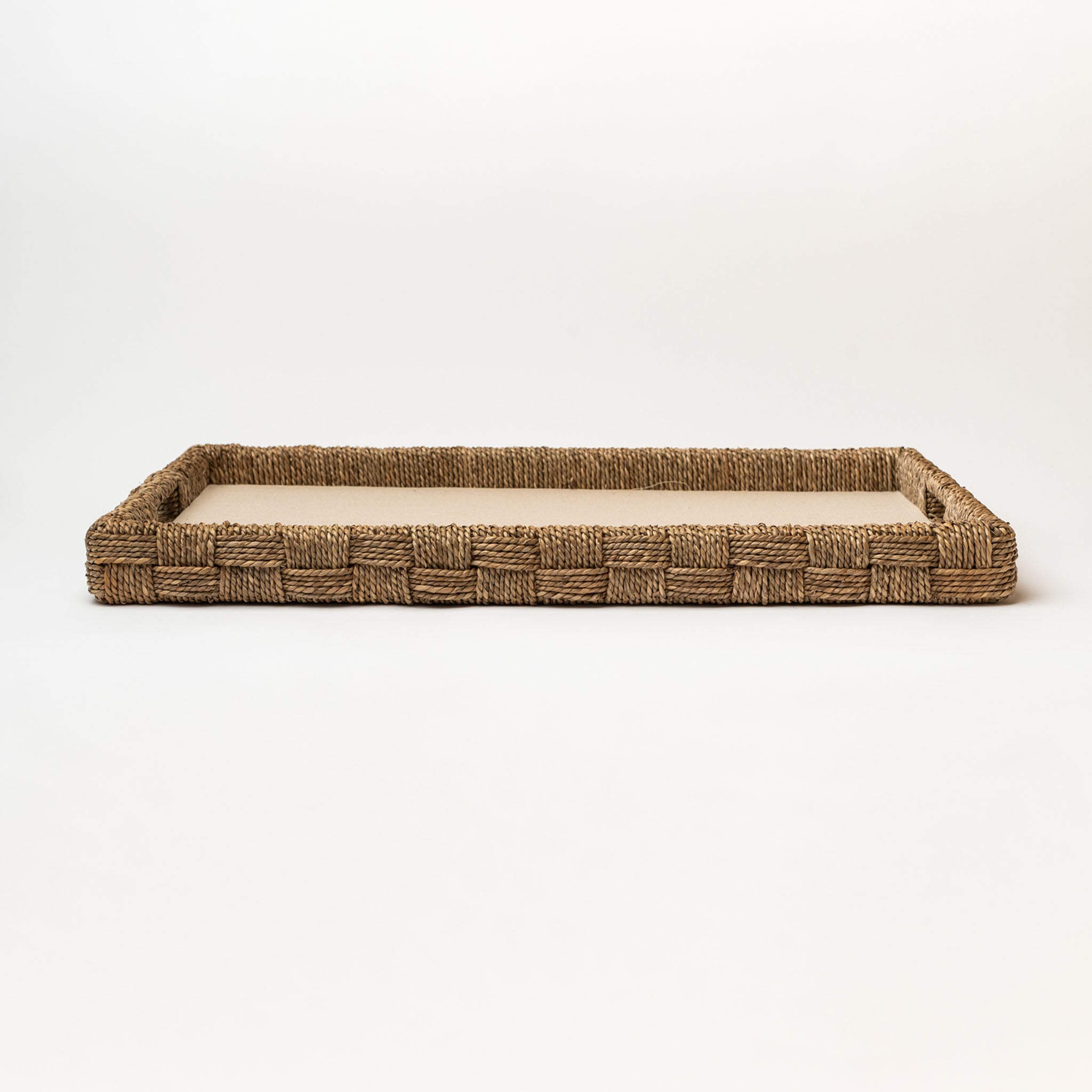 Rectangular seagrass tray with cut out handles and with linen surface on a white background