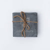 Set of four square slate Middlebury Coaster coasters tied together with natural twine on a white background