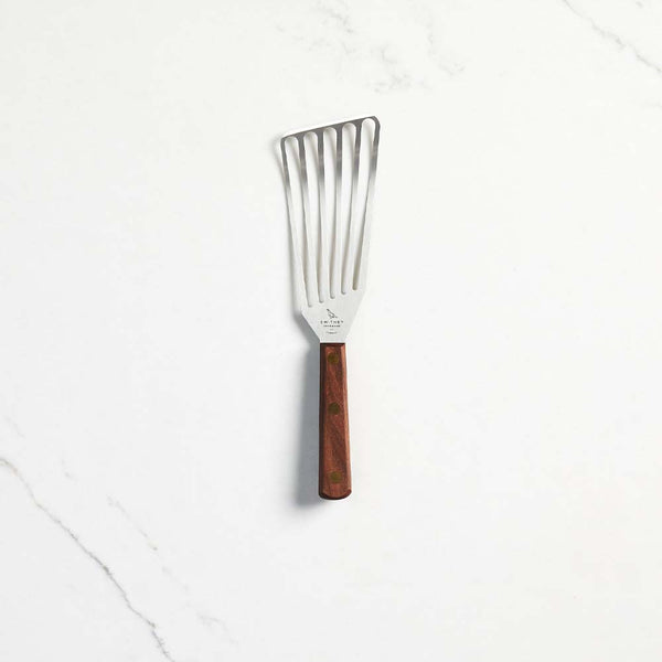 Smithey Spatula with slotted stainless steel and walnut handle on a white marble counter